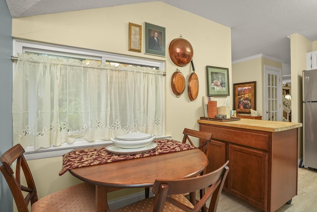 dining room with a textured ceiling, crown molding, and vaulted ceiling