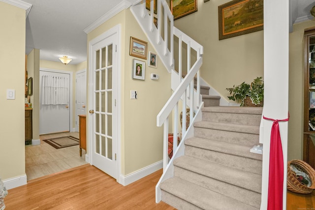 staircase featuring baseboards, wood finished floors, and crown molding