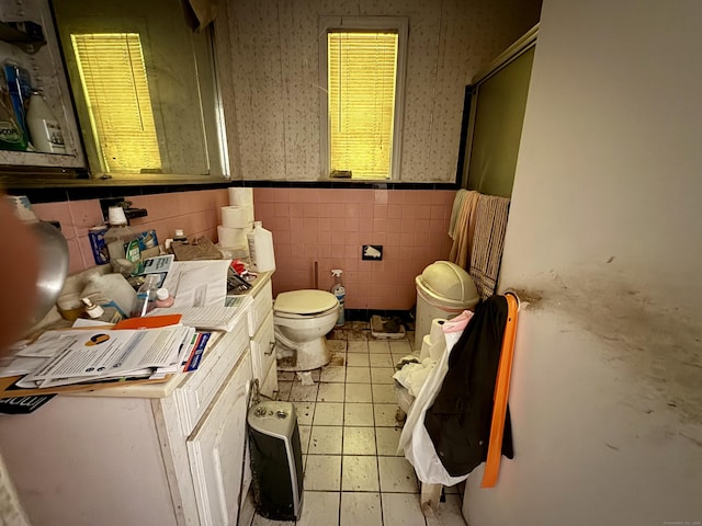 bathroom featuring wallpapered walls, tile patterned flooring, an enclosed shower, wainscoting, and toilet