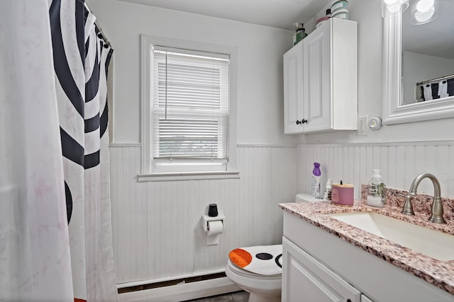 bathroom with curtained shower, a baseboard heating unit, toilet, wainscoting, and vanity