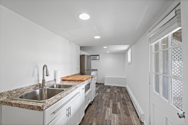 kitchen with baseboards, dark wood finished floors, recessed lighting, a sink, and white cabinets