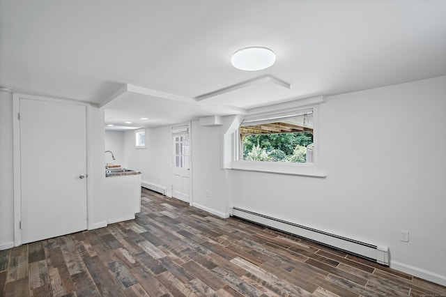 basement with a sink, dark wood-type flooring, baseboards, and a baseboard radiator