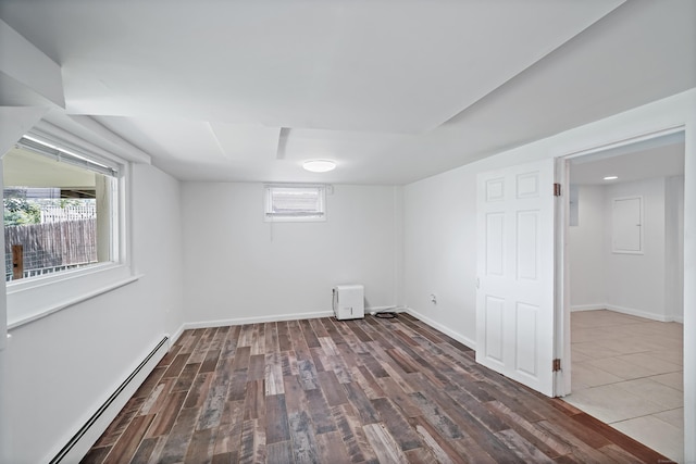 below grade area with wood finished floors, baseboards, and baseboard heating