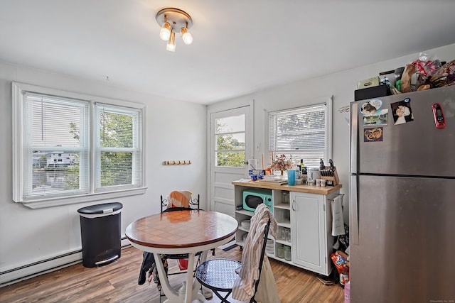 dining space with a healthy amount of sunlight, light wood-style flooring, and a baseboard radiator