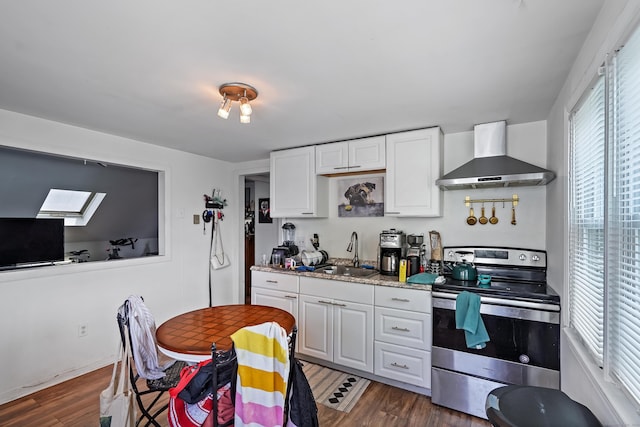 kitchen with wood finished floors, wall chimney range hood, stainless steel electric range, and a sink