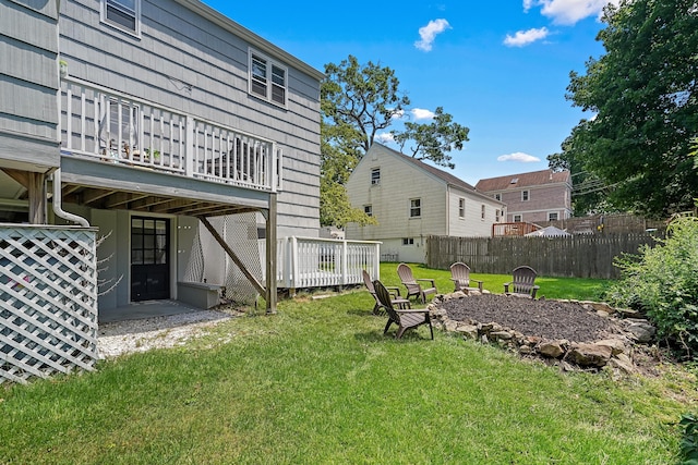 view of yard featuring a deck, fence, and an outdoor fire pit