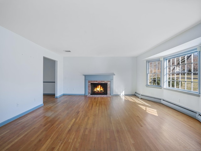 unfurnished living room featuring visible vents, a fireplace, baseboards, and wood finished floors