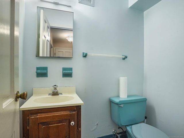 half bath with visible vents, toilet, and vanity