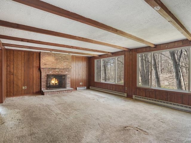 unfurnished living room with wooden walls, beam ceiling, a textured ceiling, a baseboard heating unit, and a brick fireplace