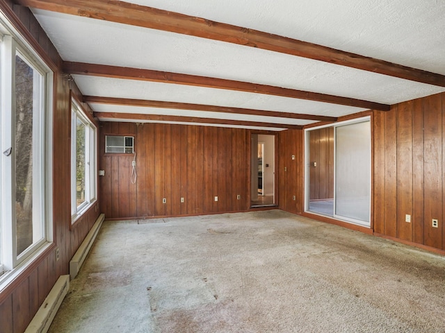 spare room featuring light colored carpet, beam ceiling, baseboard heating, and wood walls