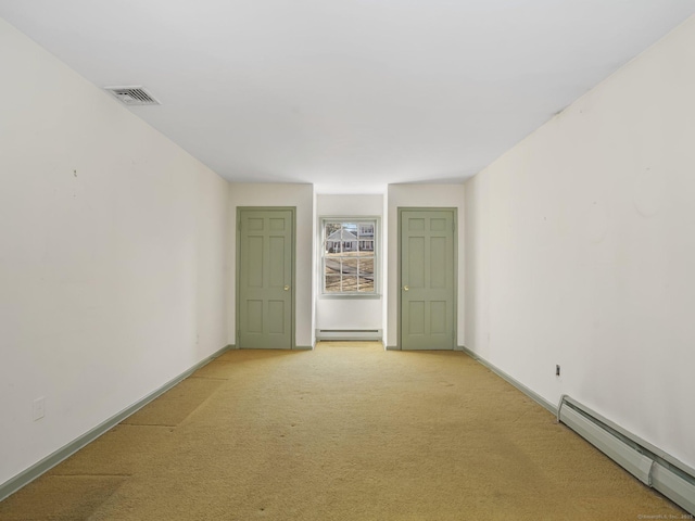 empty room featuring a baseboard heating unit, baseboards, visible vents, and light carpet