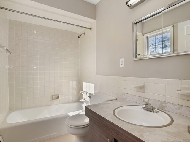 bathroom with tile patterned flooring, toilet, vanity, bathing tub / shower combination, and tile walls