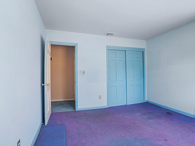 unfurnished bedroom with visible vents, baseboards, a closet, and dark carpet