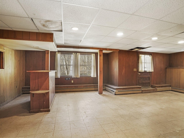 basement featuring tile patterned floors, baseboard heating, and wood walls