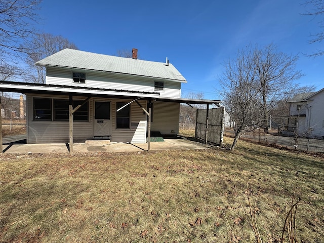 rear view of house featuring an attached carport, a chimney, a lawn, and entry steps