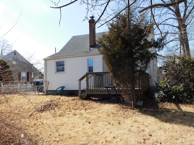 rear view of house with a wooden deck, fence, and a chimney