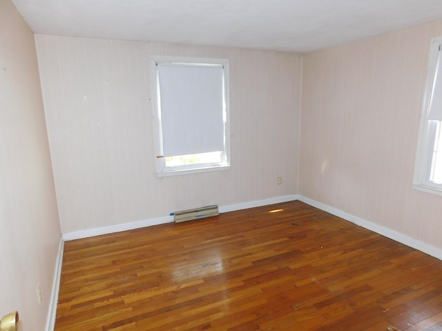 unfurnished room with baseboard heating, baseboards, and wood-type flooring