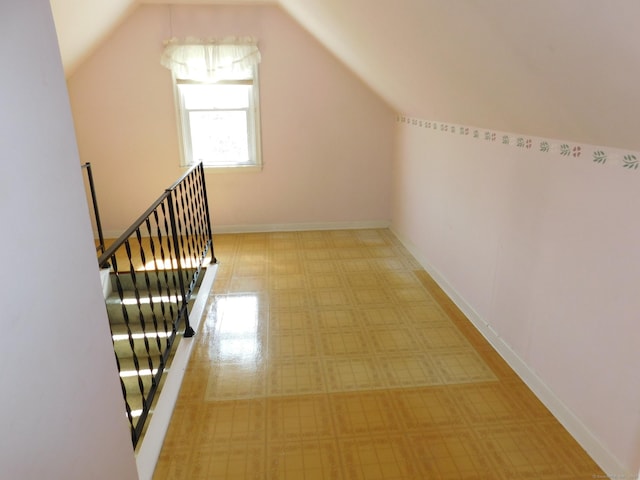 corridor featuring baseboards, lofted ceiling, and an upstairs landing