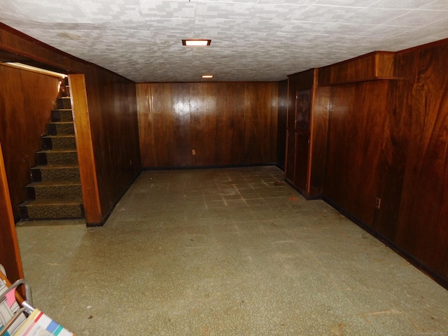 finished basement featuring wooden walls and stairs