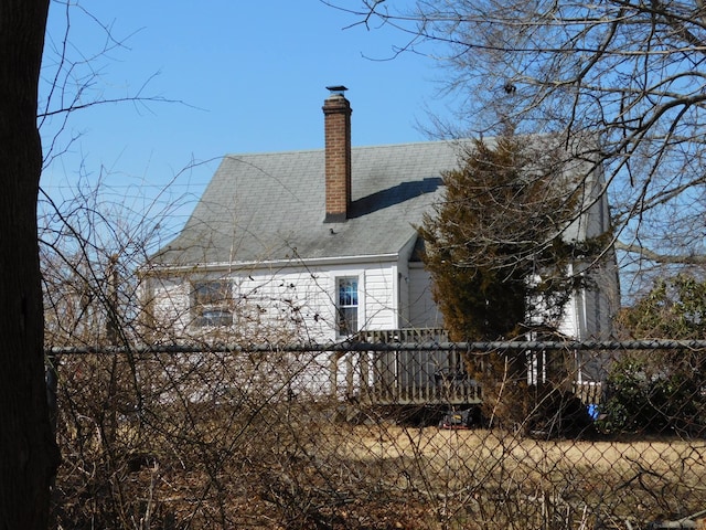 rear view of house featuring a chimney and fence