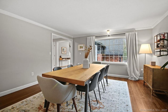 dining space with baseboards, wood finished floors, and ornamental molding