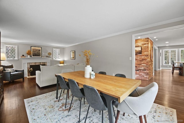 dining area featuring ornamental molding, dark wood-style floors, recessed lighting, a fireplace, and baseboards