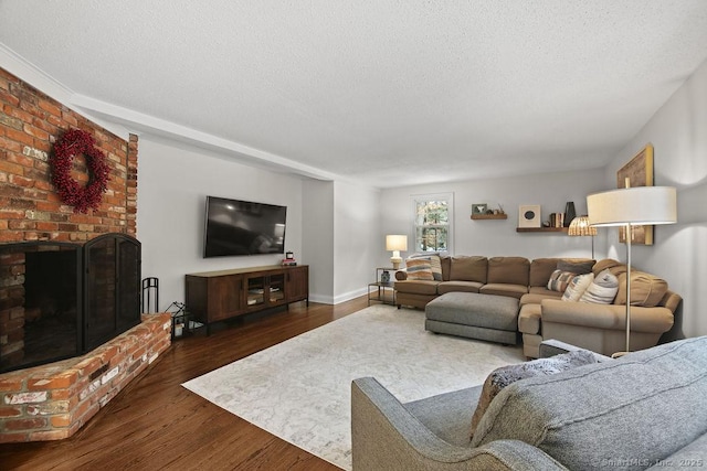 living area featuring a fireplace, a textured ceiling, baseboards, and wood finished floors