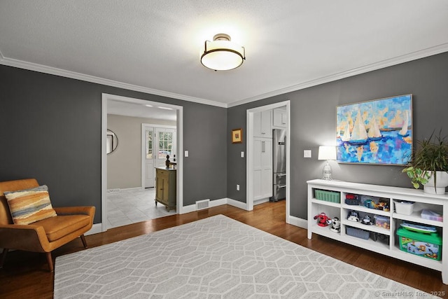 living area featuring crown molding, wood finished floors, visible vents, and baseboards