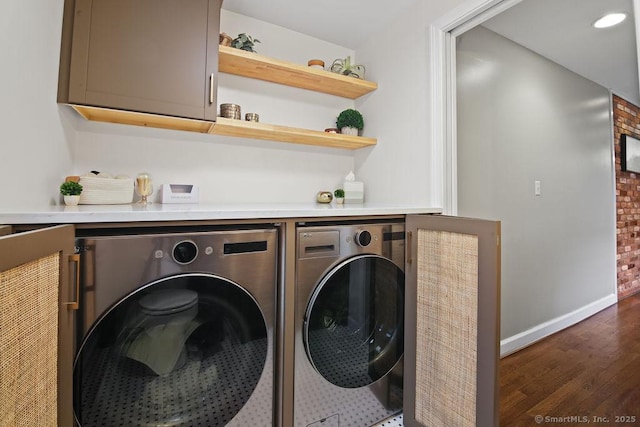 clothes washing area featuring wood finished floors, washing machine and dryer, cabinet space, and baseboards