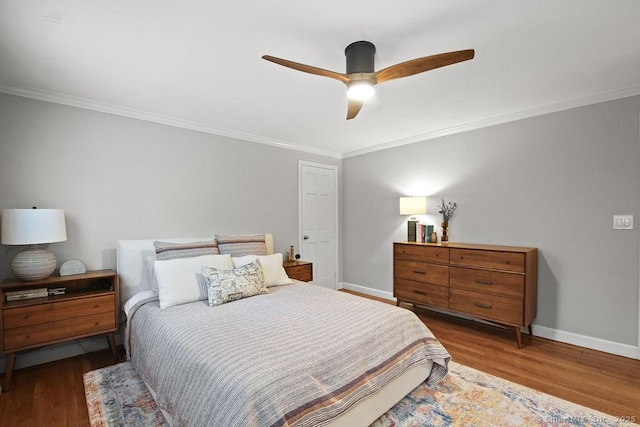 bedroom featuring baseboards, wood finished floors, and crown molding