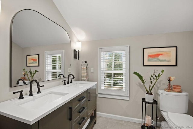 bathroom featuring vaulted ceiling, toilet, baseboards, and a sink