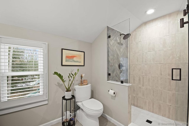 bathroom with toilet, tiled shower, and vaulted ceiling