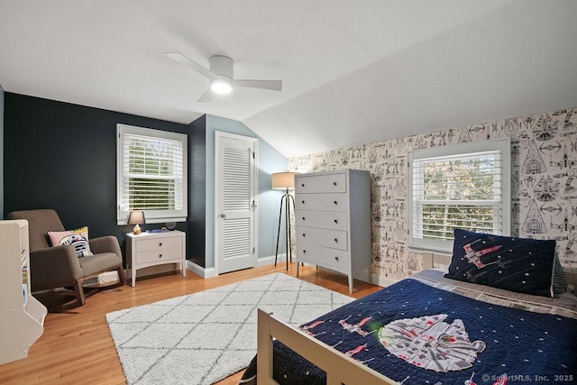 bedroom with baseboards, light wood-style flooring, wallpapered walls, and lofted ceiling