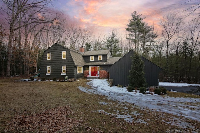 dutch colonial with a gambrel roof, a chimney, and a shingled roof