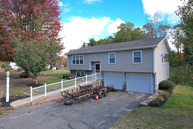 split foyer home with fence, an attached garage, a chimney, a front lawn, and aphalt driveway