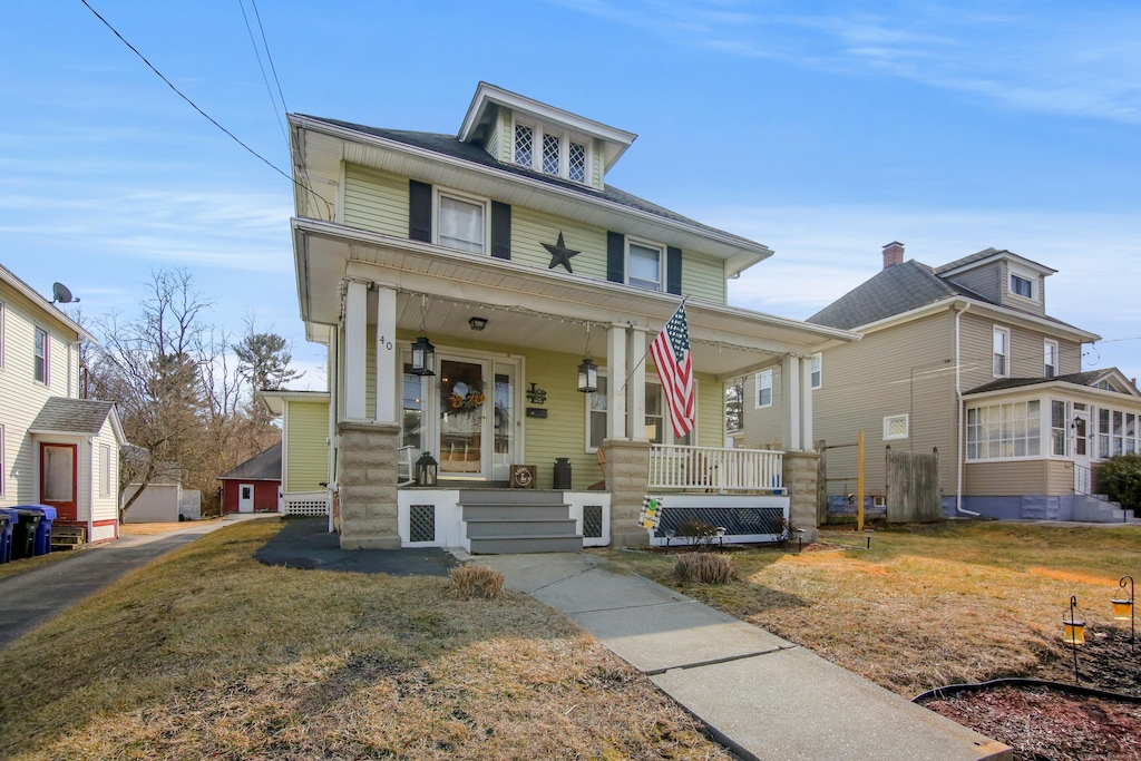 american foursquare style home with covered porch and a front lawn