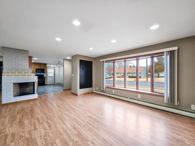 unfurnished living room featuring recessed lighting, light wood-type flooring, baseboard heating, and a brick fireplace