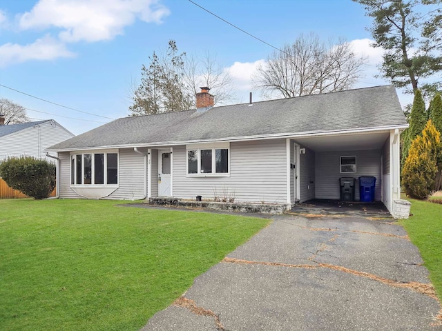 ranch-style house with an attached carport, roof with shingles, a chimney, a front lawn, and aphalt driveway