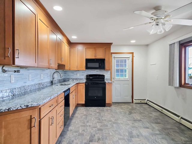 kitchen with black appliances, light stone counters, a sink, backsplash, and baseboard heating