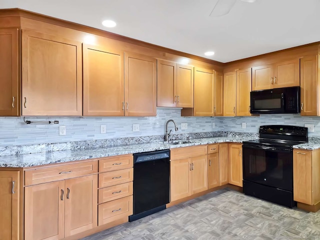 kitchen featuring light brown cabinetry, light stone counters, decorative backsplash, black appliances, and a sink