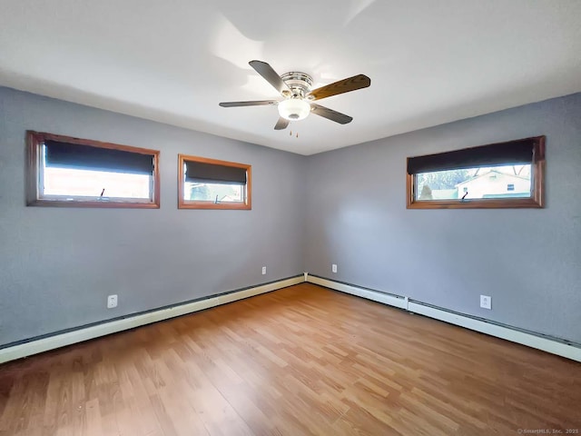 spare room with baseboard heating, a ceiling fan, and wood finished floors