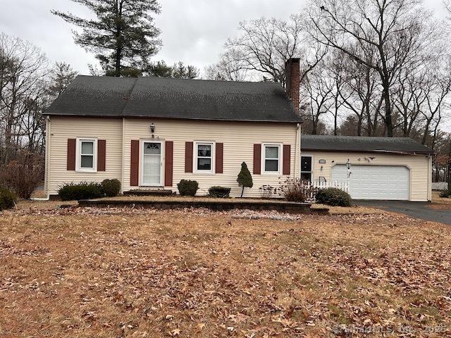 view of front facade with a garage, a chimney, and aphalt driveway