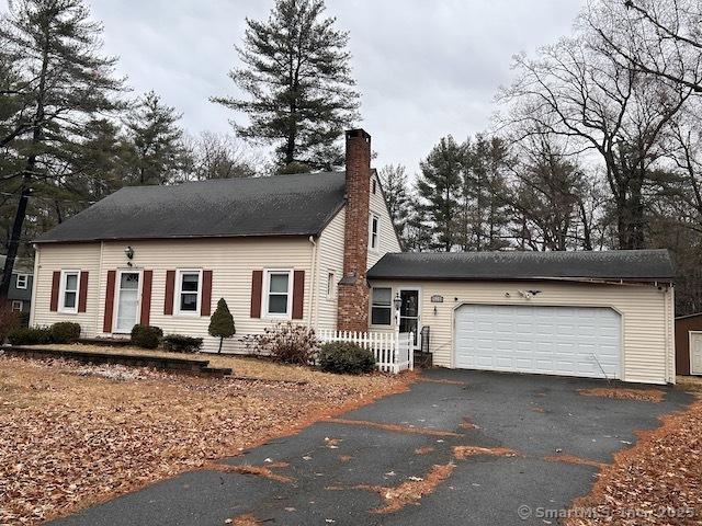 view of front of home with driveway, an attached garage, and a chimney