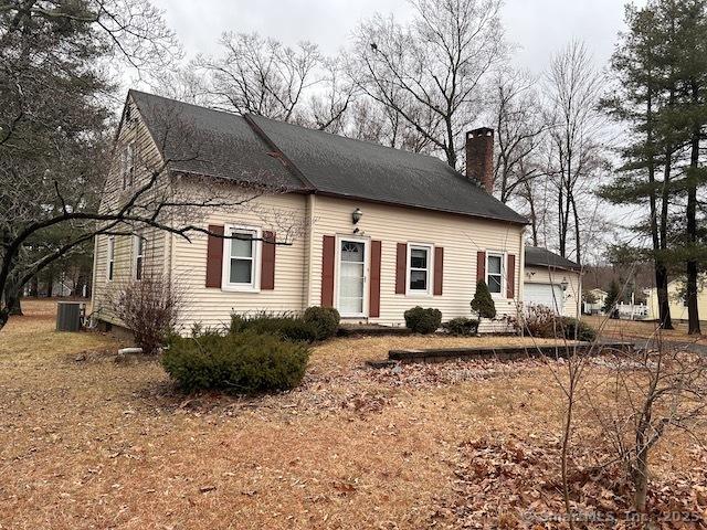 view of front of home with cooling unit, a chimney, and a garage