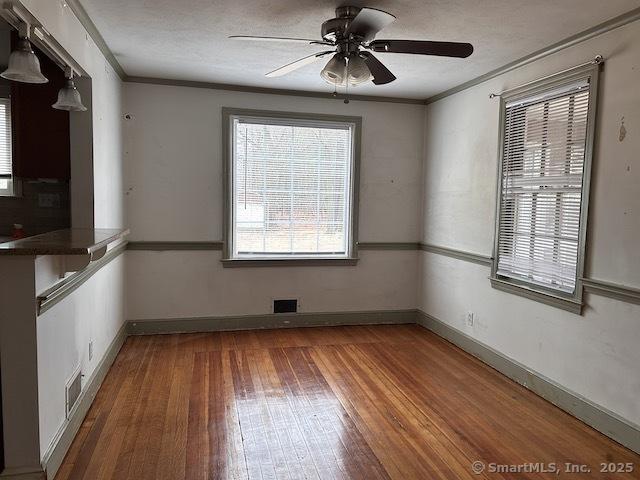 unfurnished dining area with baseboards, ornamental molding, and hardwood / wood-style flooring