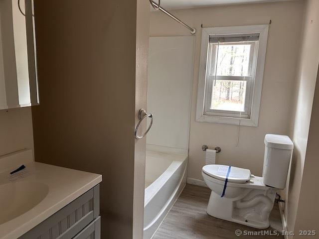 bathroom with toilet, vanity, bathtub / shower combination, and wood finished floors