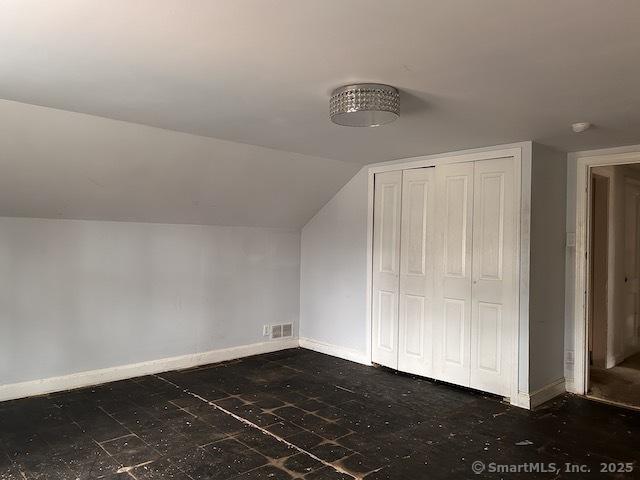 additional living space with lofted ceiling, baseboards, and visible vents