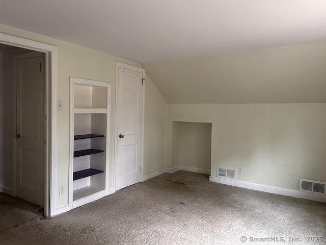 additional living space featuring vaulted ceiling, carpet flooring, baseboards, and visible vents