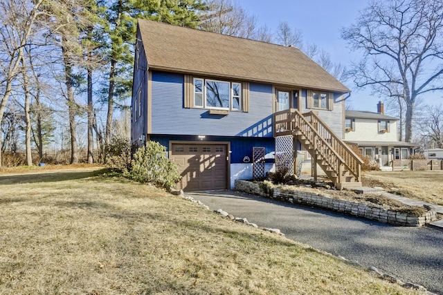 view of front of house with a front lawn, a garage, driveway, and roof with shingles