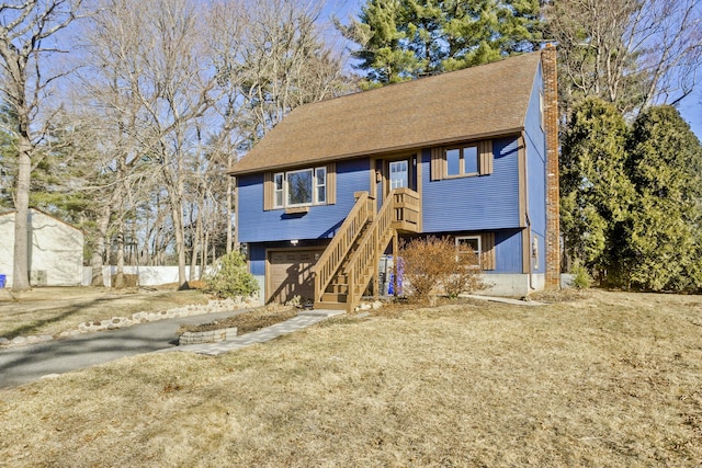 view of front of property featuring a garage, roof with shingles, and a chimney